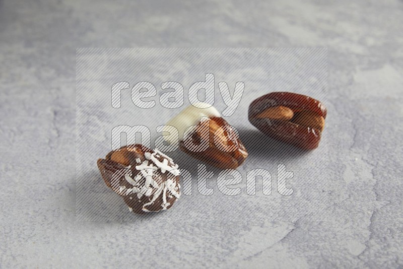 Three Almond stuffed dates plain and covered with chocolate on a light grey background