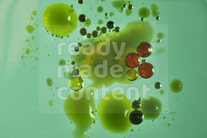 Close-ups of abstract red, green and yellow watercolor drops on oil Surface on green background