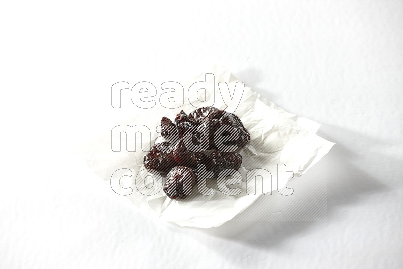 Dried plums on a crumpled piece of paper on a white background in different angles