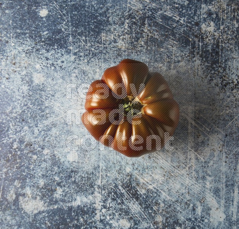 Single Topview Heirloom Tomato on a textured rustic blue background