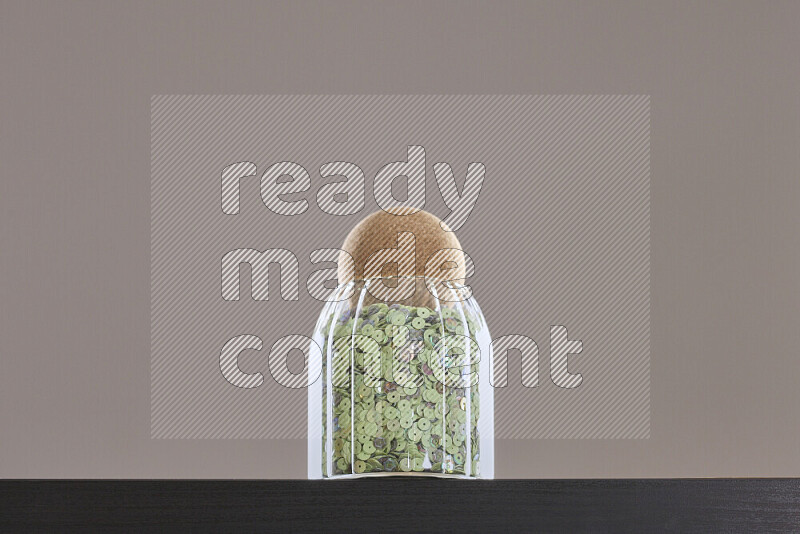 Sequins in a glass jar on black background