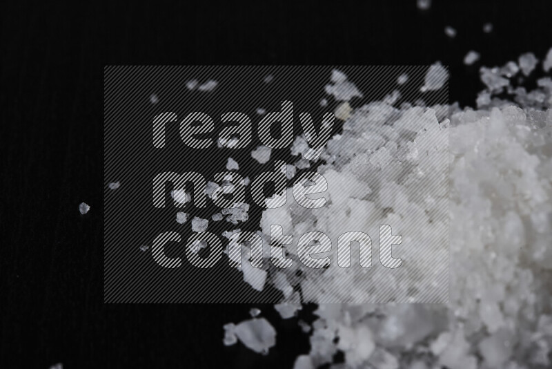 A bunch of coarse sea salt crystals on black background