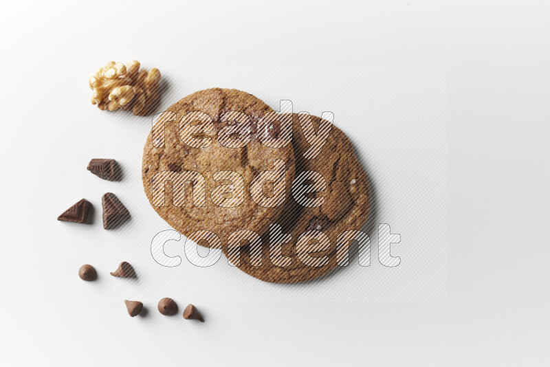 Chocolate chips cookies with chocolate and walnuts beside it on a white background