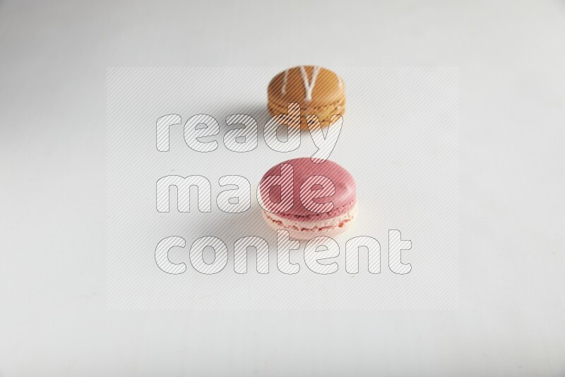 45º Shot of of two assorted Brown Irish Cream, and Pink Litchi Raspberry macarons on white background