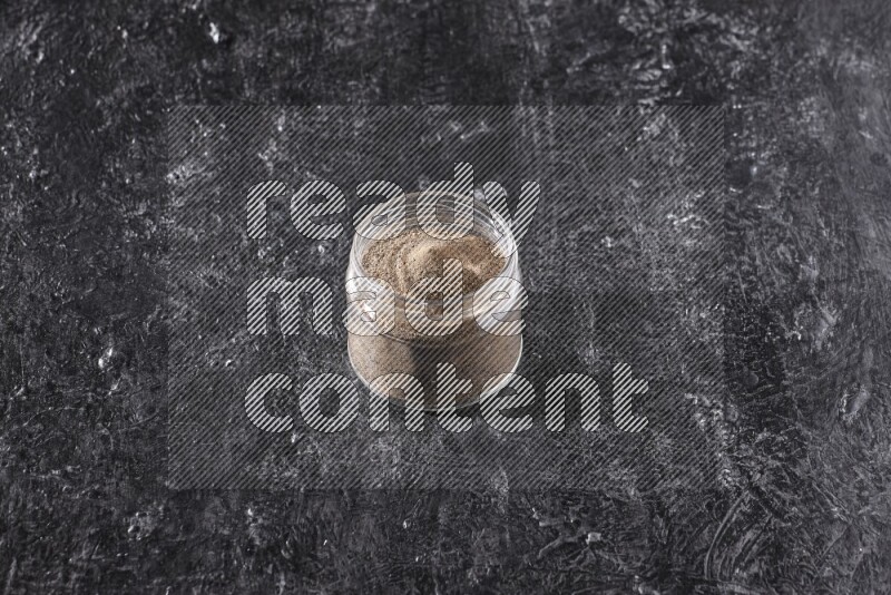 بودرة الفلفل الأسود في وعاء زجاجي علي خلفية سوداء