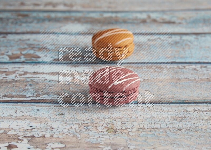 45º Shot of of two assorted Brown Irish Cream, and Red Poppy Flower macarons  on light blue background