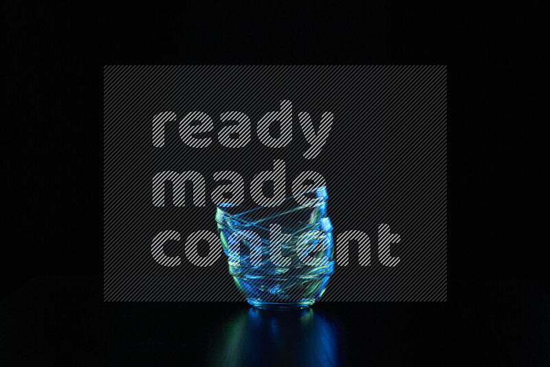 Glassware with rim light in blue and green against black background