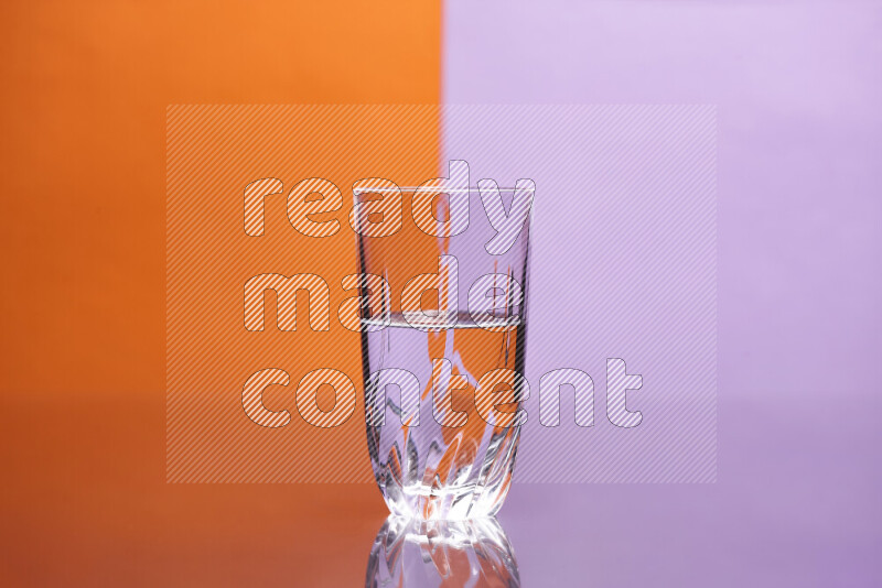 The image features a clear glassware filled with water, set against orange and light purple background