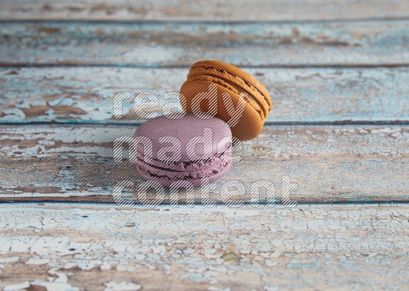 45º Shot of of two assorted Brown Irish Cream, and Purple Blueberry macarons  on light blue background