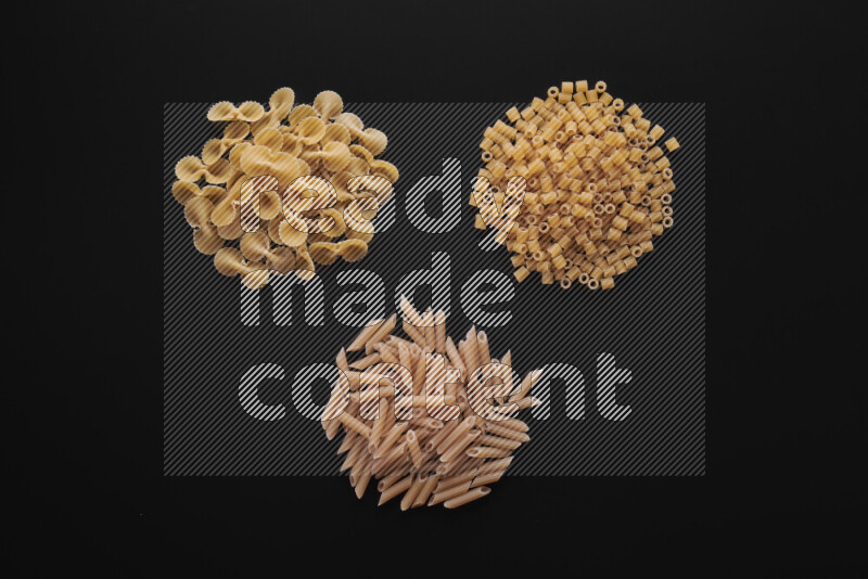 Different pasta types in bunches on black background