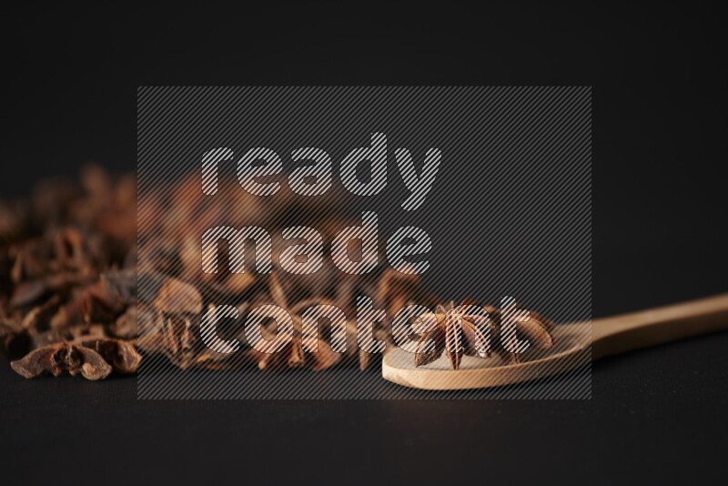 اليانسون النجمي في ملعقة خشبية ومتناثر على أرضية سوداء