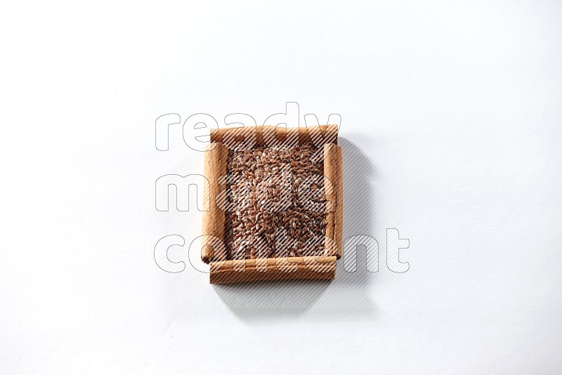 A single square of cinnamon sticks full of flaxseeds on white flooring
