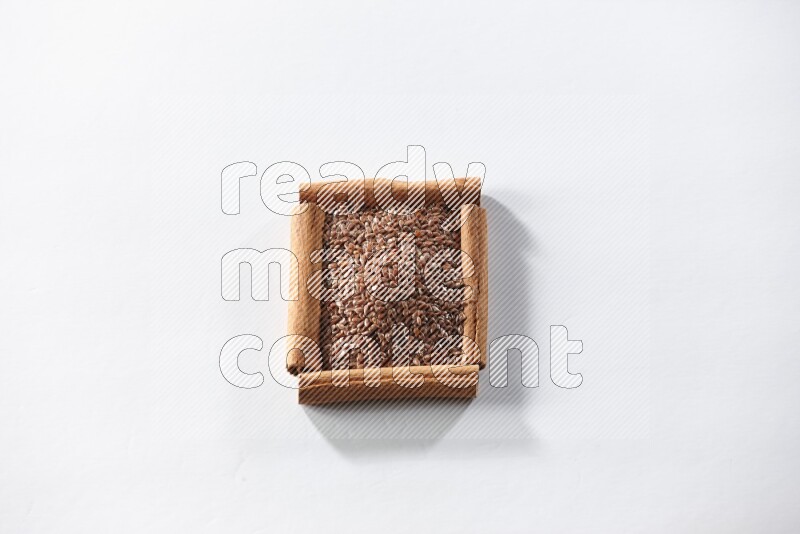 A single square of cinnamon sticks full of flaxseeds on white flooring