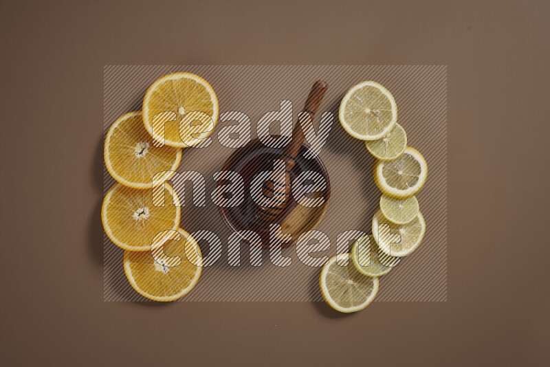 A bowl full of honey with some of citrus fruits such as lemon and orange on a beige background