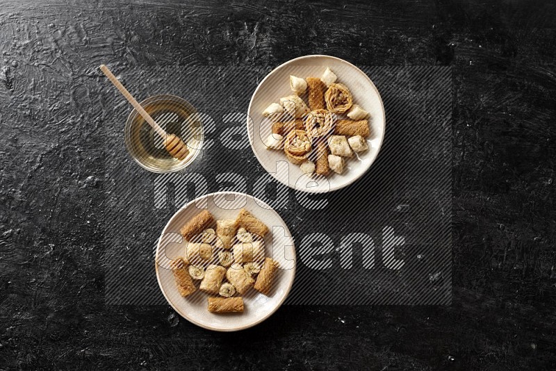 Oriental sweets in pottery plates with honey in a dark setup
