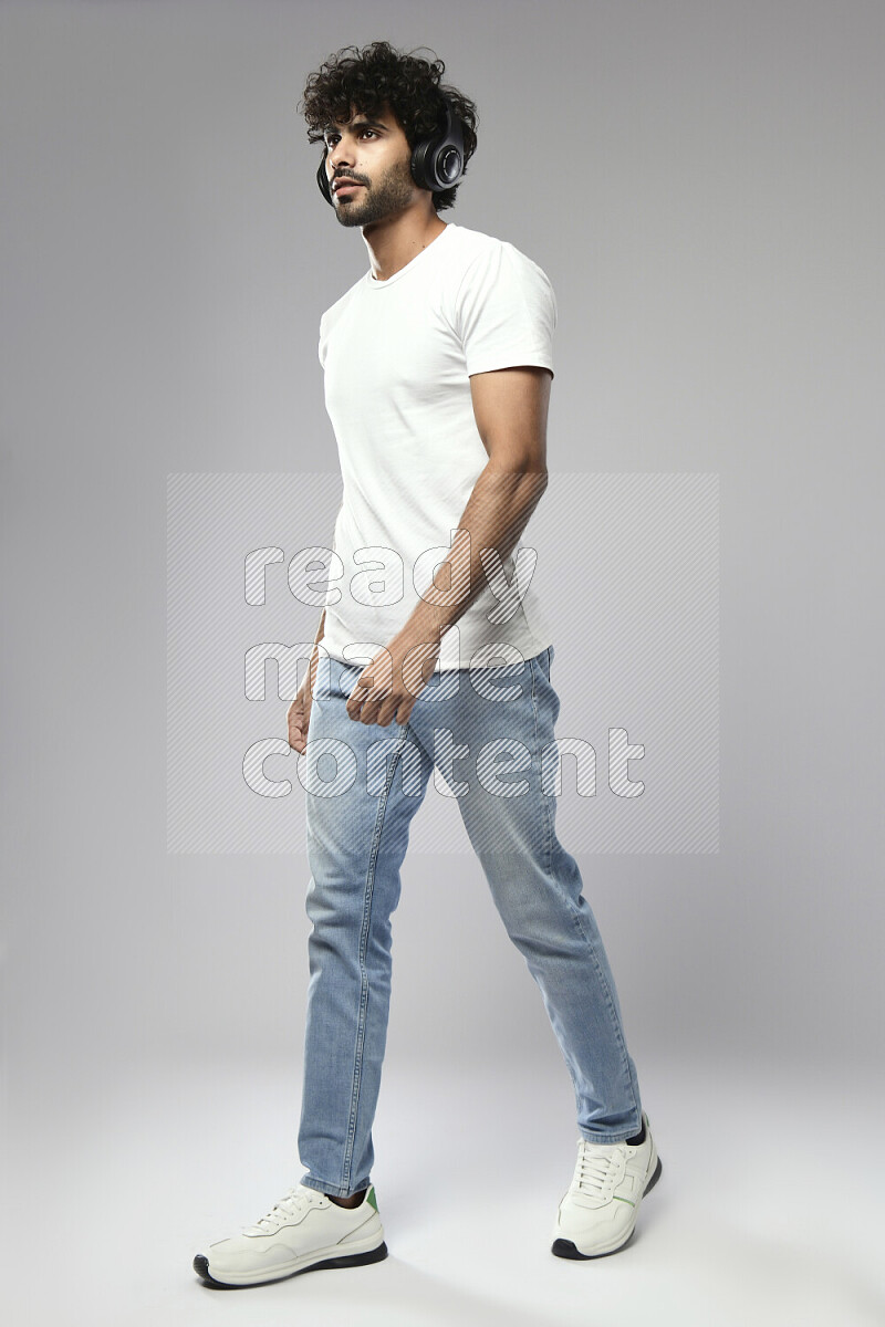 A man wearing casual standing and putting on headphones on white background