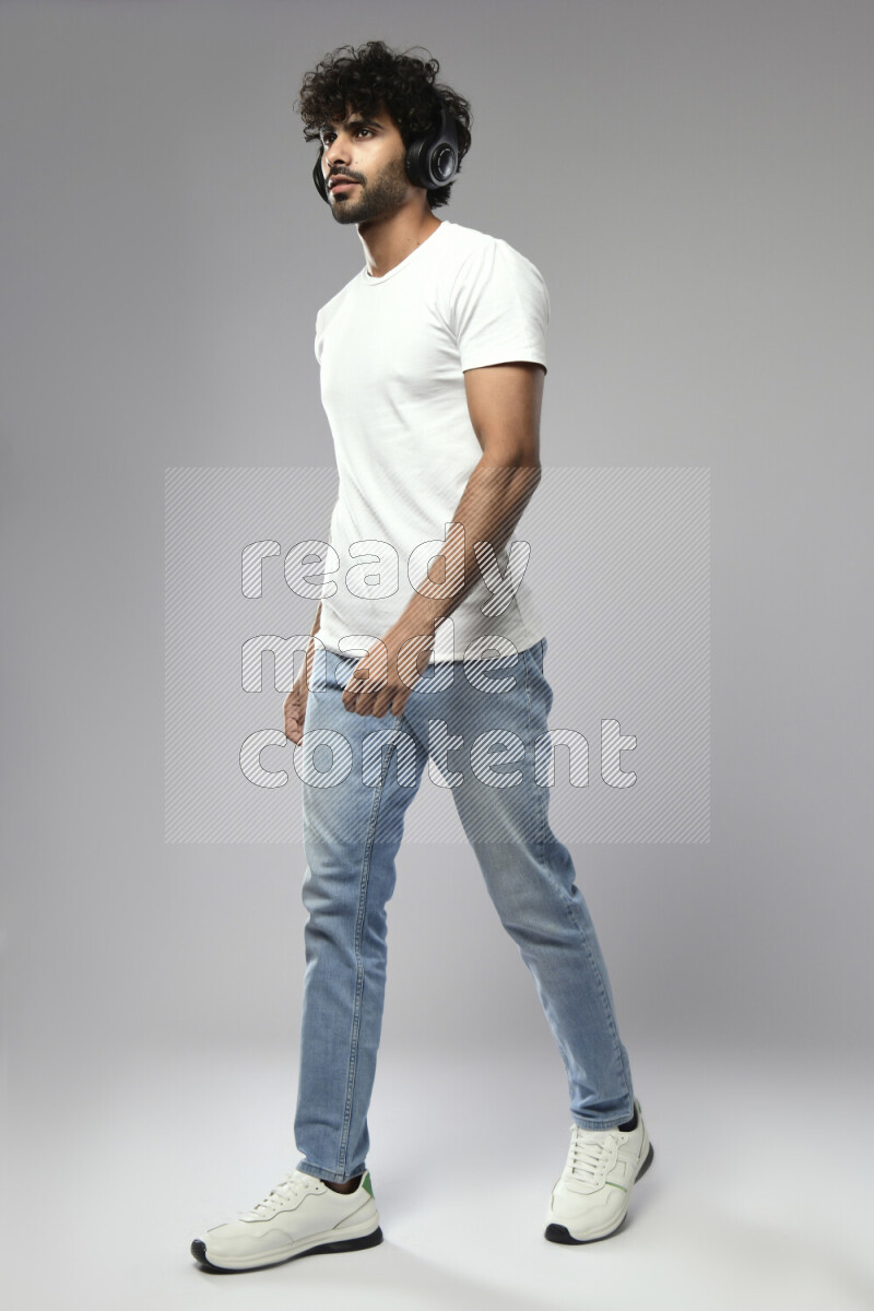 رجل يرتدي ملابس كاجوال يضع سماعات رأس علي خلفية بيضاء