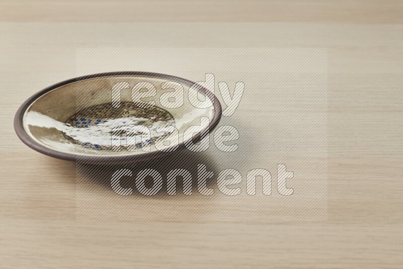 A decorative pottery plate on light wooden background