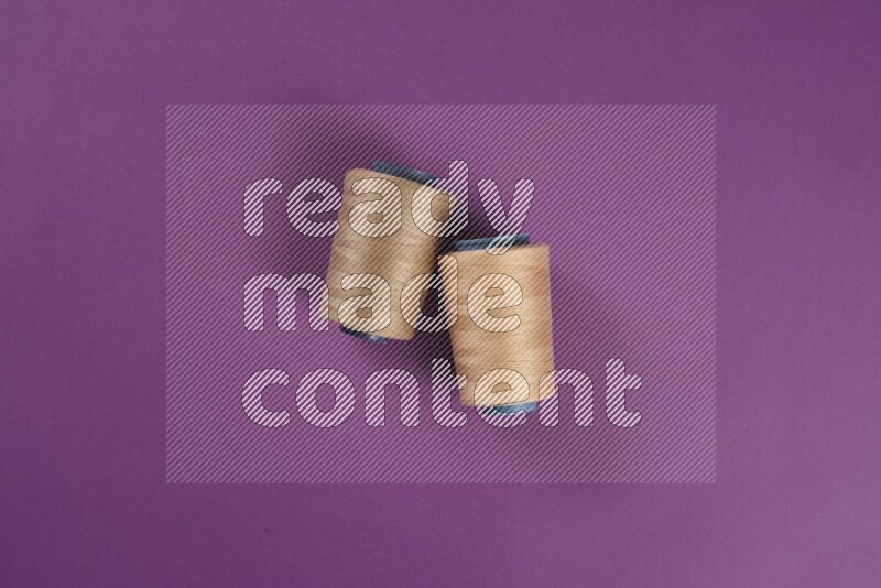 A beige collection of sewing and tailoring tools arranged on a purple background