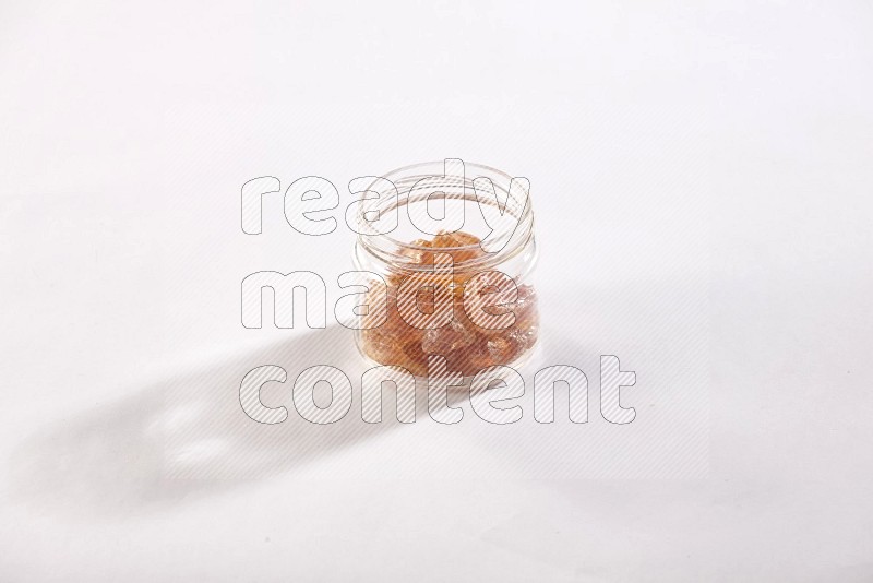 A glass jar filled with gum arabic on white flooring in different angles