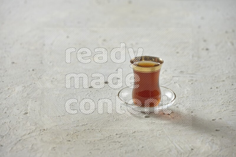 A tea glass cup with dates and coffee on textured white background