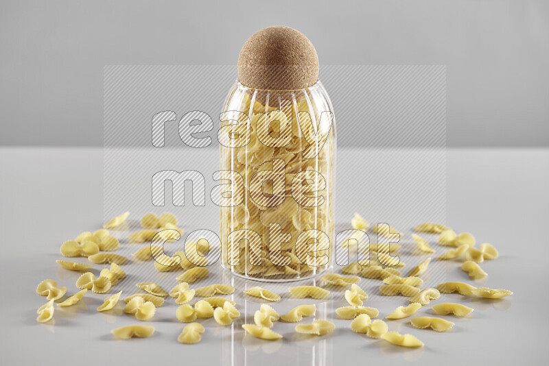 Raw pasta in a glass jar on light grey background