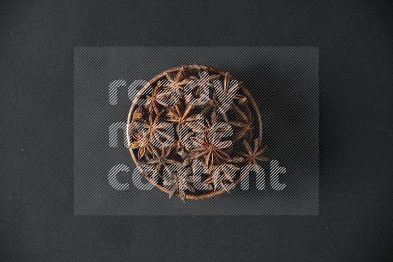 Star Anise in a wooden bowl on black flooring