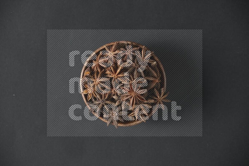 Star Anise in a wooden bowl on black flooring