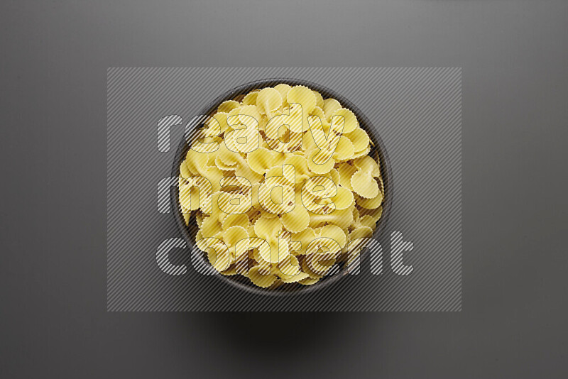 Fiocchi pasta in a pottery bowl on grey background