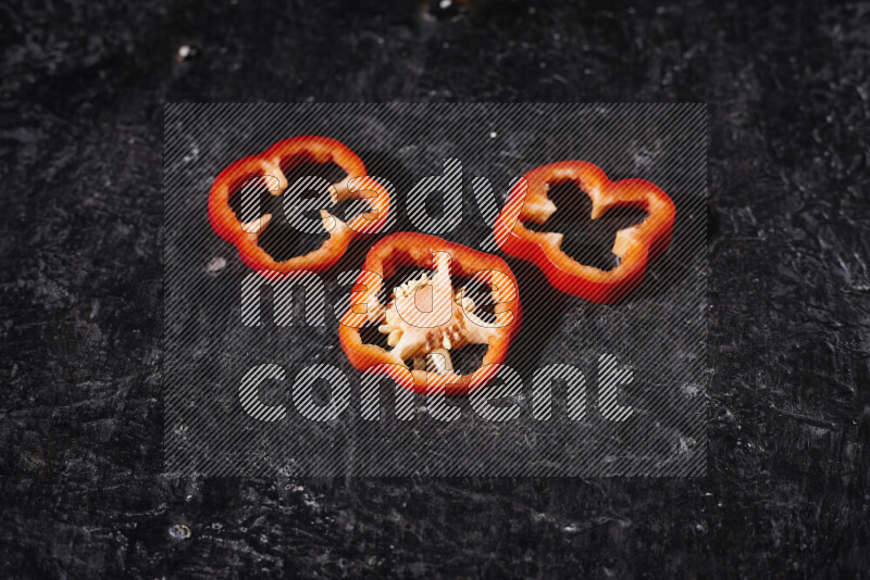 Red bell pepper slices on black background
