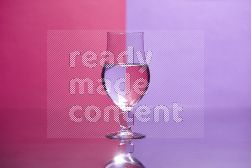 The image features a clear glassware filled with water, set against pink and light purple background