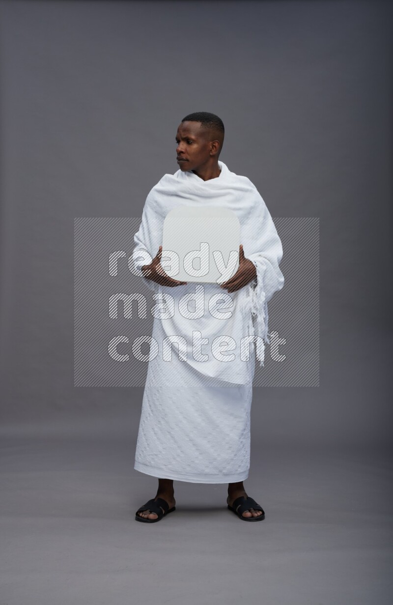A man wearing Ehram Standing holding social media sign on gray background
