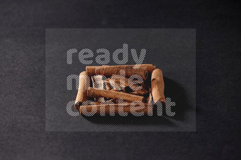 A single square of cinnamon sticks full of cinnamon on black flooring