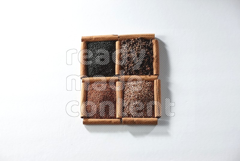 4 squares of cinnamon sticks full of black seeds, cloves, flaxseeds and garden cress on white flooring