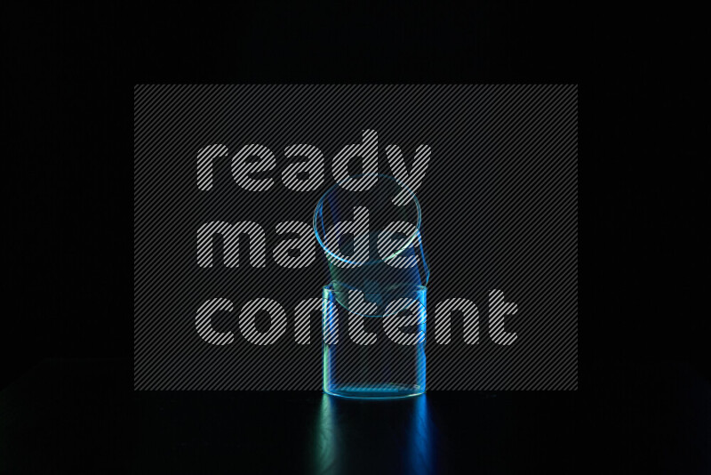 Glassware with rim light in blue and green against black background