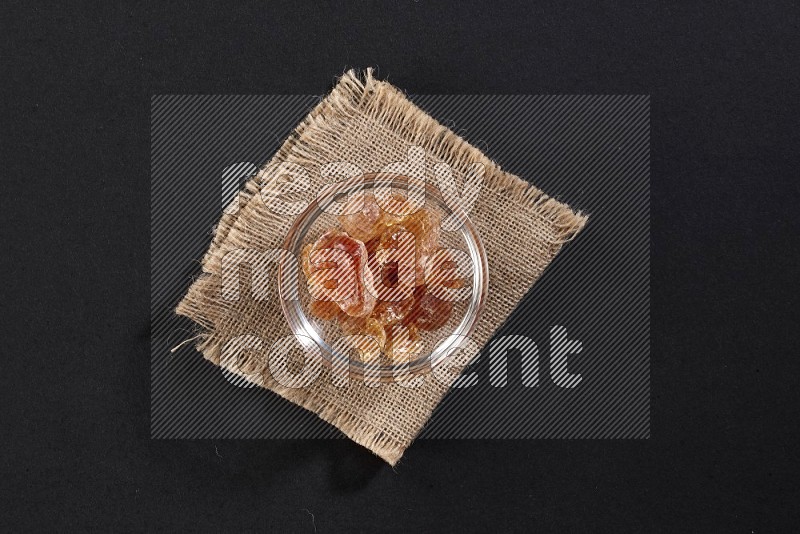 A glass bowl full of gum arabic on a burlap piece on black flooring in different angles