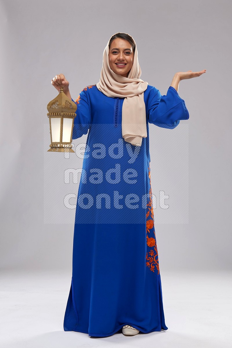 A Saudi woman standing wearing Jalabeya holding a lantern