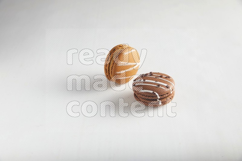 45º Shot of of two assorted Brown Irish Cream, and Brown white Chocolate Caramel macarons on white background