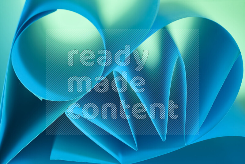 An artistic display of paper folds creating a harmonious blend of geometric shapes, highlighted by soft lighting in green and blue tones