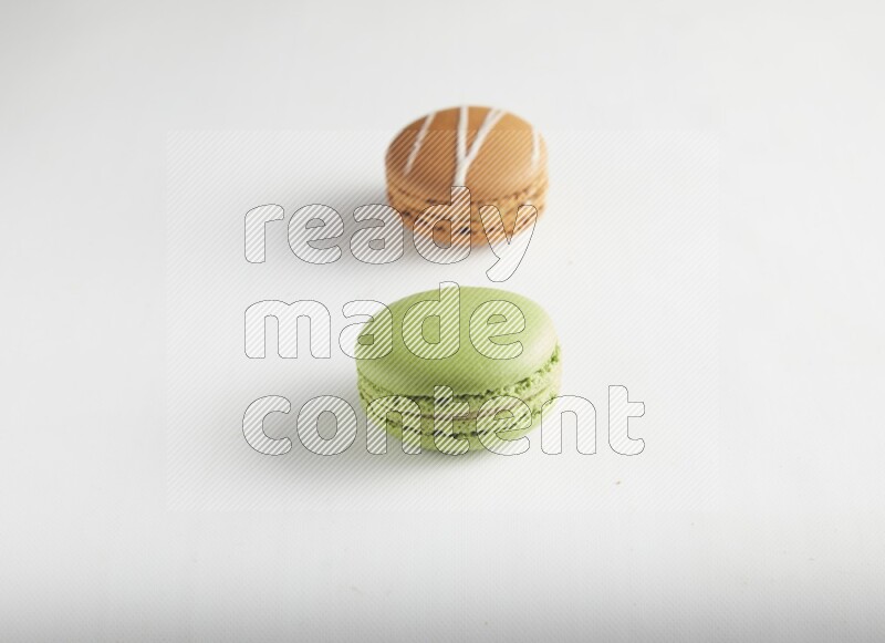 45º Shot of of two assorted Brown Irish Cream, and Green Pistachio macarons on white background