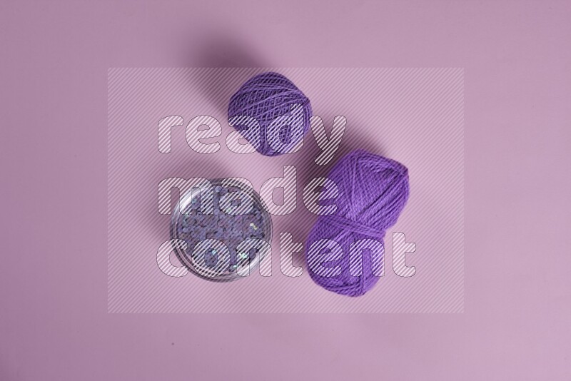 A purple and pink collection of sewing and tailoring tools arranged on a pink background