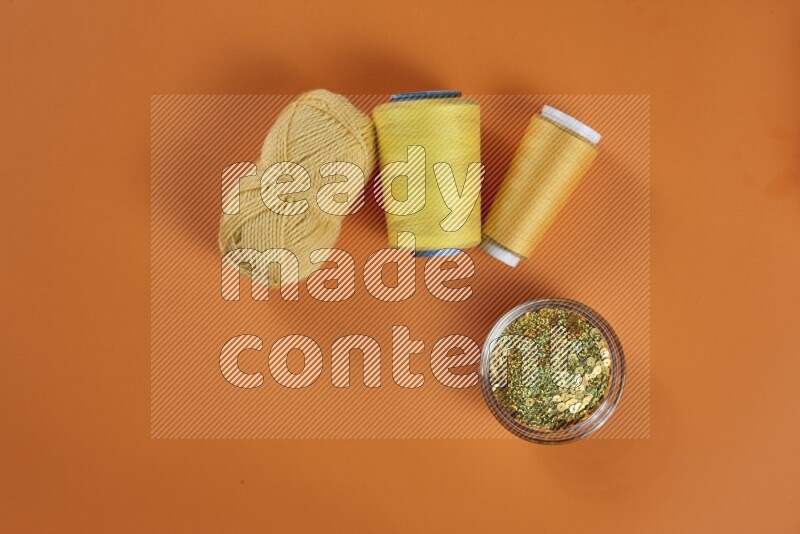 مجموعة من أدوات الخياطة والتفصيل صفراء اللون على خلفية برتقالية