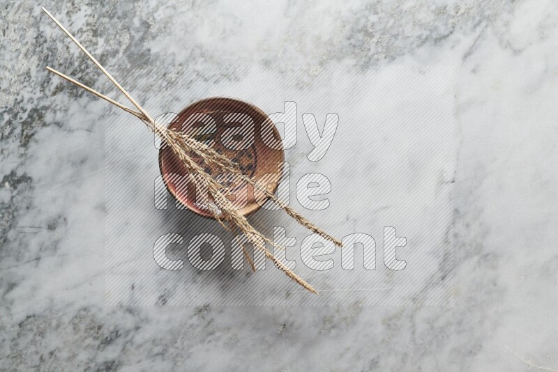 Wheat stalks on decorative pottery plate on grey marble background