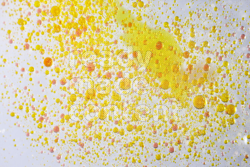لقطات مقربة لقطرات ألوان مائية صفراء وحمراء على سطح الزيت على خلفية بيضاء