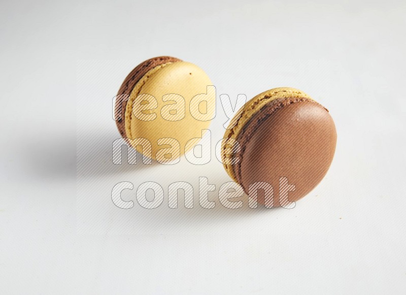 45º Shot of two Yellow and Brown Chai Latte macarons on white background