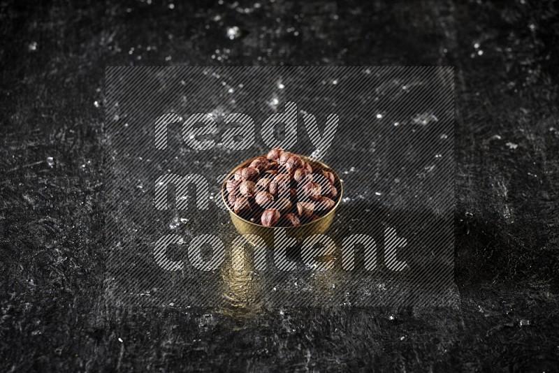 Nuts in a metal bowl in a dark setup