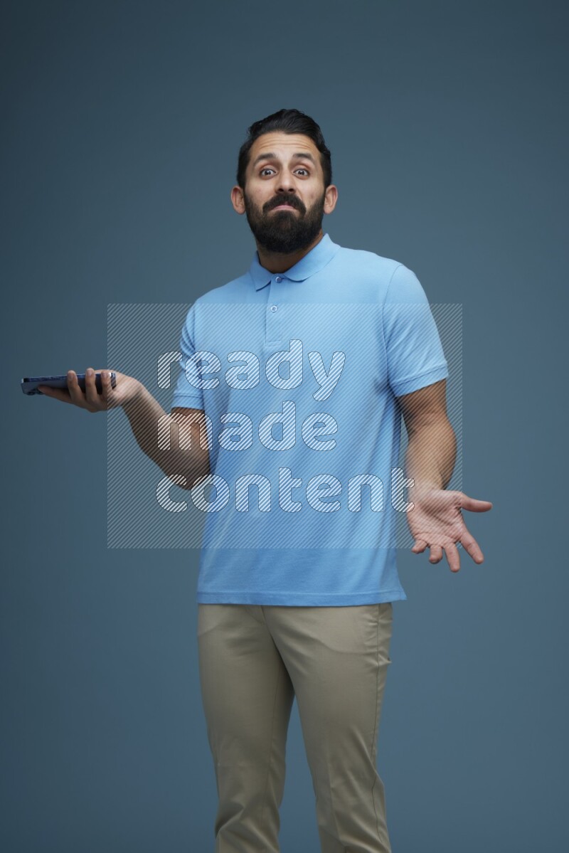 Man posing with a phone in a blue background wearing a Blue shirt