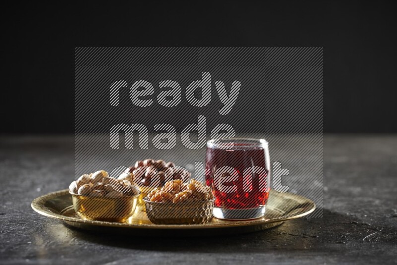 Nuts in metal bowls with Hibiscus on a tray in dark setup