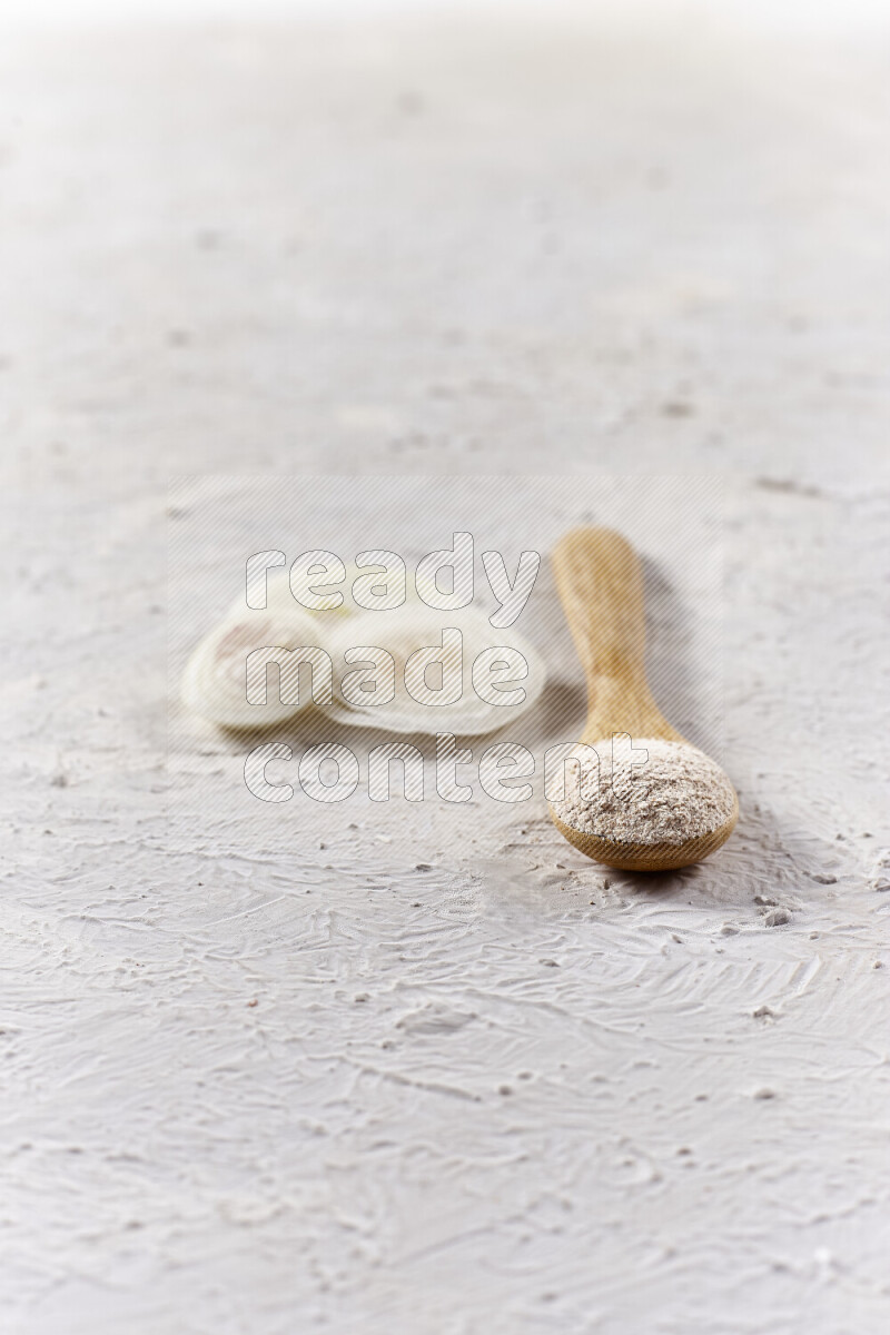 A wooden spoon full of onion powder on white background