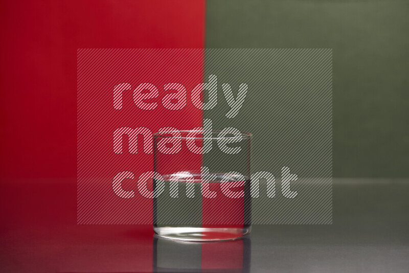 The image features a clear glassware filled with water, set against red and dark green background